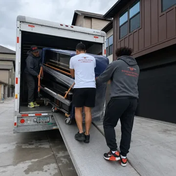 Piano movers loading a piano up the truck ramp in Portland, Oregon