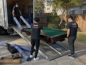 Pool table unloaded from a moving truck on a ramp with the rails staged — Seattle pool table movers