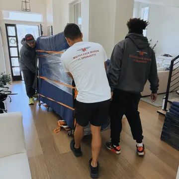 Piano movers Utah moving a fully wrapped upright piano on a dolly