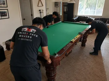 Movers installing the slate on a pool table frame in Utah